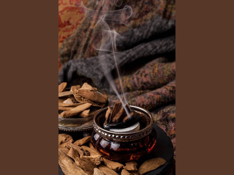 Incense smoke rising in a column, the kind of heavy plume that signals the heat is too high for bakhoor
